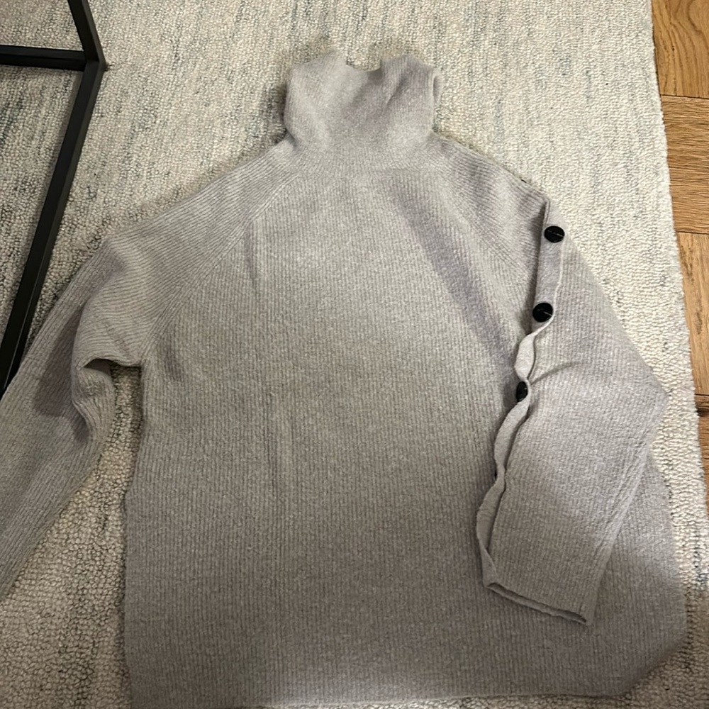 Long sleeve sweater with button accents on sleeves.